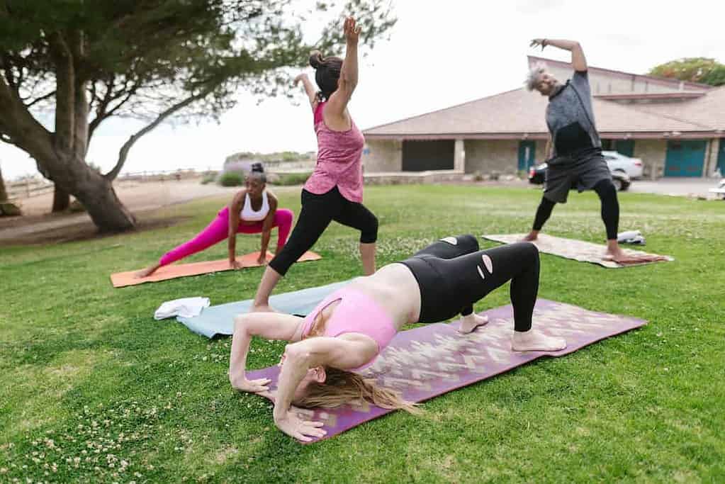 outdoor yoga class with a teacher and three students doing various yoga flow sequences